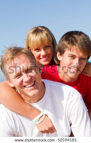 happy mid-aged father and children on beach