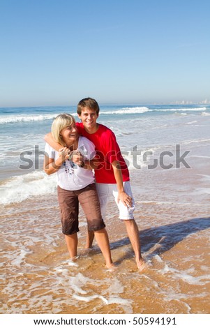 middle-aged mother and teen son playing on beach