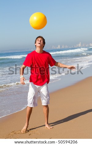 stock photo teen boy playing beach ball on beach