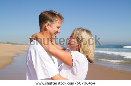 Happy mid-aged couple embracing on a sunny day at the beach