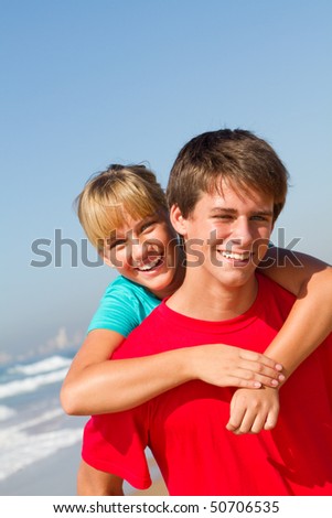 teen brother and sister piggyback on beach
