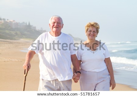 happy senior couple walking on beach
