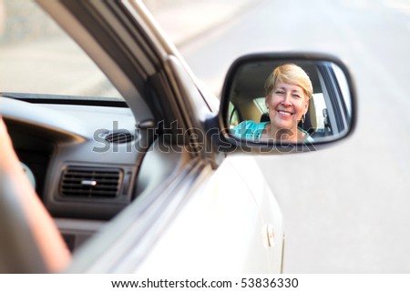 happy senior driver looking at side mirror