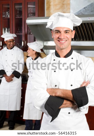 happy male professional chefs in industrial kitchen with colleagues behind