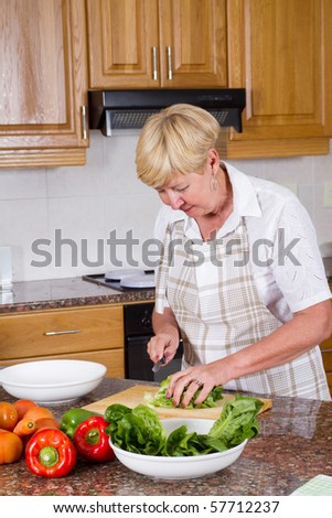 Happy senior woman making a healthy salad in kitchen