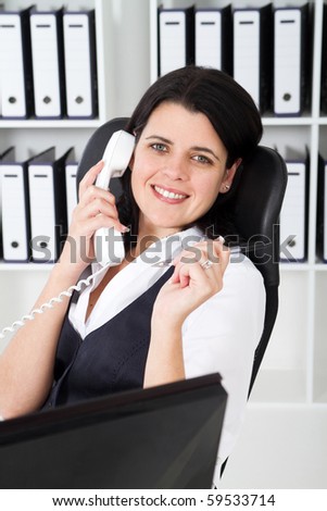 young businesswoman answering telephone in office