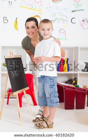 preschool boy and teacher in front of black board in classroom