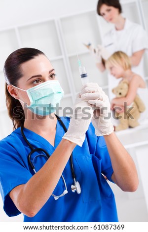paediatrician with syringe in office, background is nurse and child patient