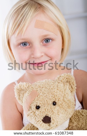 Little girl with band-aid on her face holding a teddy bear