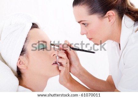 professional female makeup artist applying makeup to model\'s face