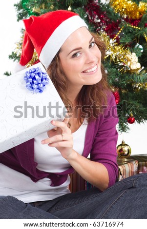 happy young woman under a Christmas tree holding Christmas gift