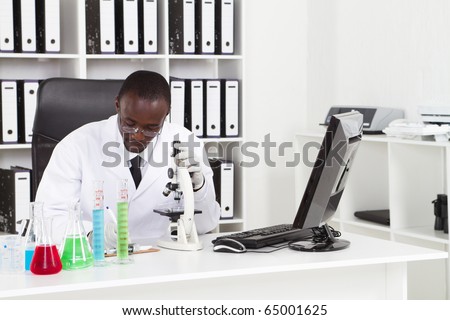 african american medical scientist wearing lab coat with microscope and test tubes in laboratory