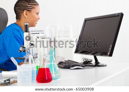female african american scientist in lab, focus on liquid in front