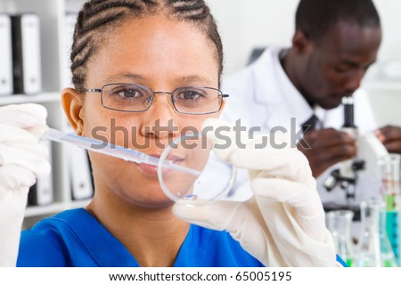 stock-photo-african-american-female-scientist-doing-experiment-in-lab-background-is-her-colleague-working-on-65005195.jpg