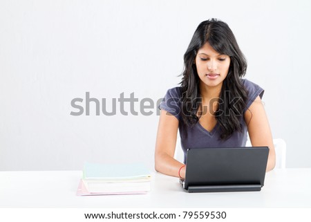 young female indian college student using a laptop in classroom