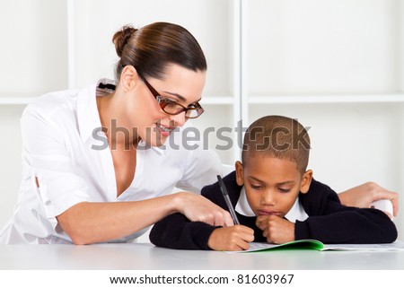 caring elementary teacher helping schoolboy