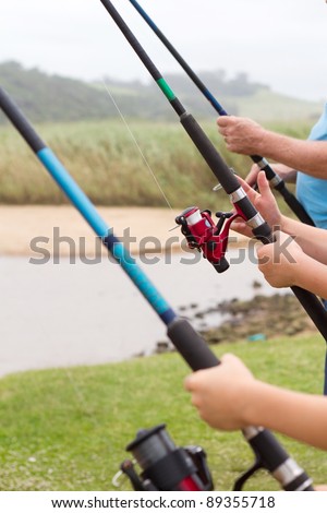 closeup of three people holding fishing rods