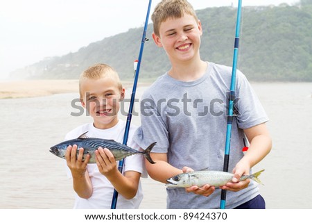 brothers holding two fish and showing their catch of the day