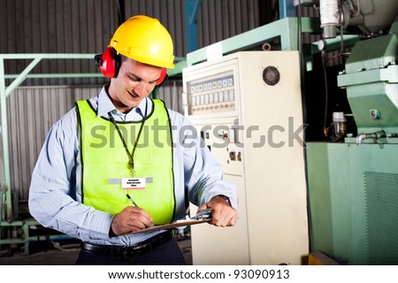 male occupational health and safety officer inside factory doing inspection male occupational health and safety officer inside factory doing inspection