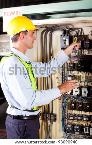 industrial technician checking machine control box temperature