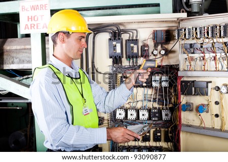 male caucasian electrician checking industrial machine control box temperature