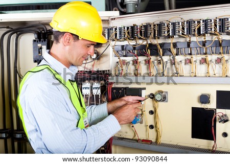 male caucasian electrician changing industrial machine switch