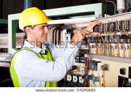 male electrician repairing industrial machine control component
