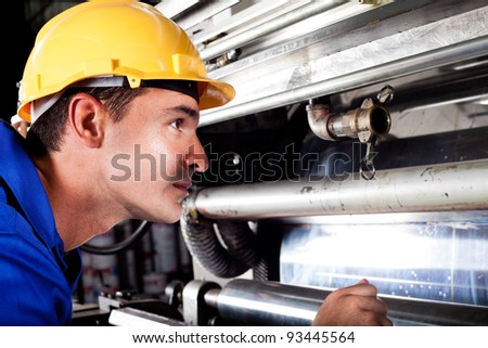 industrial machine operator checking on machine while it\'s running