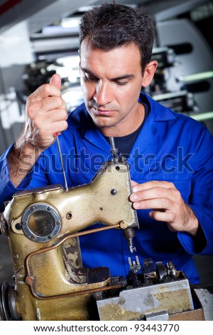 mechanic repairing industrial sewing machine in factory