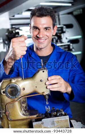happy industrial mechanic repairing sewing machine