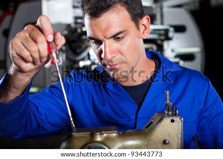 mechanic repairing industrial sewing machine