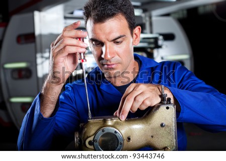 skilled mechanic repairing industrial sewing machine in factory