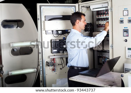 technician repairing industrial machine with laptop computer