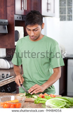 young casual indian man cooking in kitchen