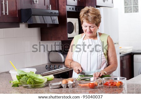 elderly woman cooking food in home kitchen