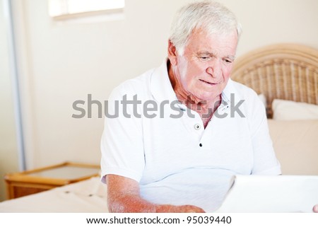 senior man sitting on bed and reading newspaper