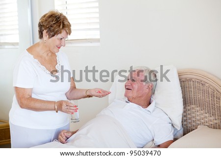 caring senior wife giving medicine to ill husband