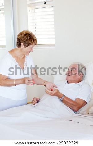 caring senior wife giving medicine to ill husband