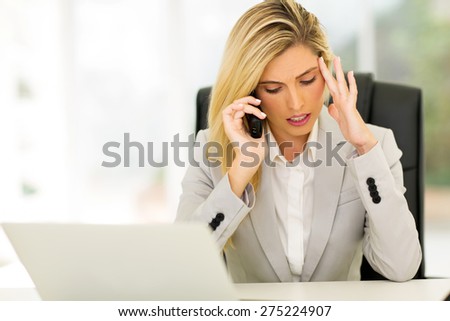 stressed businesswoman talking on telephone in office
