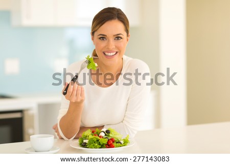 healthy young woman eating green salad at home
