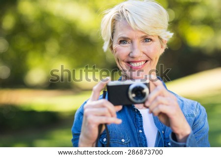pretty middle aged woman with her camera at the park