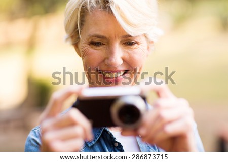 happy middle aged woman viewing pictures on camera