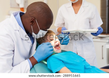 african american male dentist examining patient\'s teeth in dental clinic