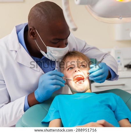 professional african dentist working on little patient
