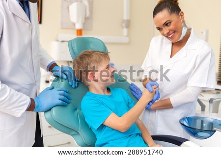 caring female dental assistant greeting little patient before checkup