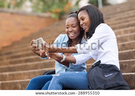 beautiful african american college students using cell phone on campus