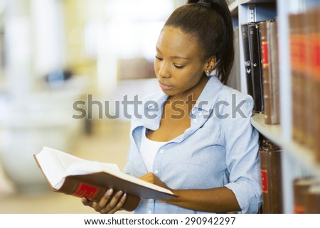 young female african university student reading a book in library