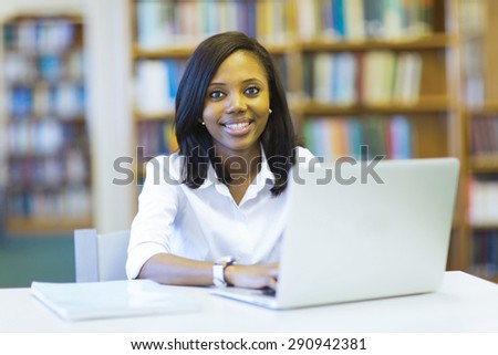 smiling female african university student using laptop