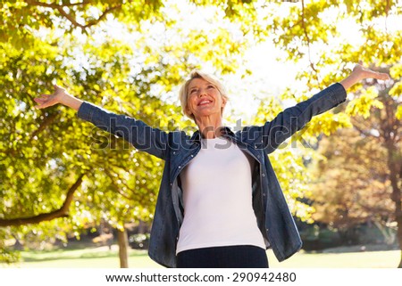 low angle view of happy mid age woman with arms outstretched outdoors