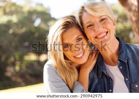 happy middle aged blond mother and adult daughter outdoors